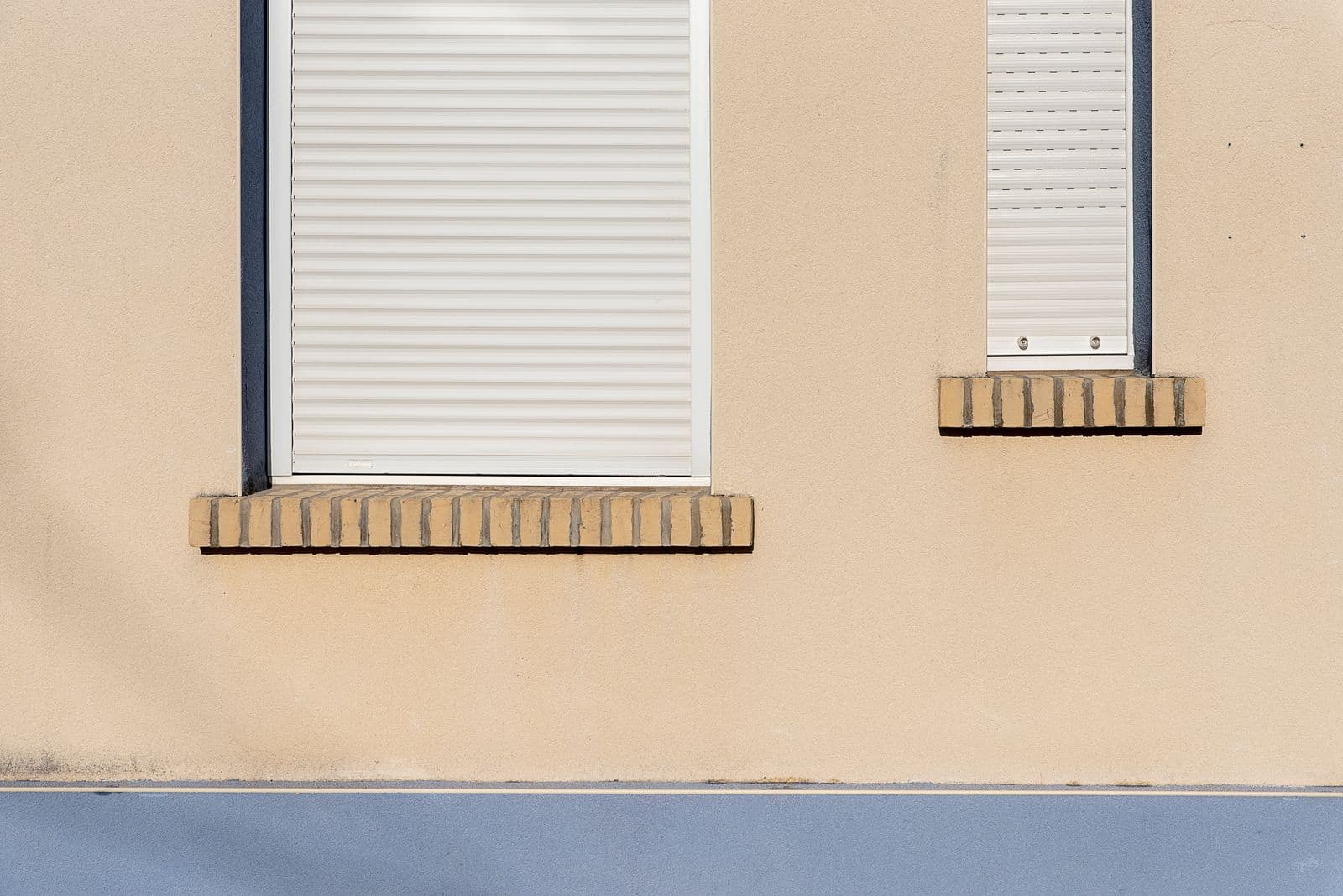 Volets roulants blancs fermés sur une façade beige